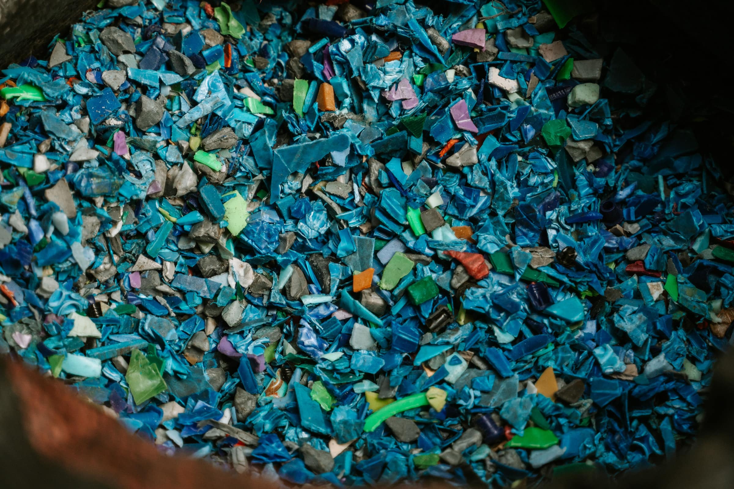 Molido de plástico rígido reciclado, en su mayoría azul, dentro de un costal