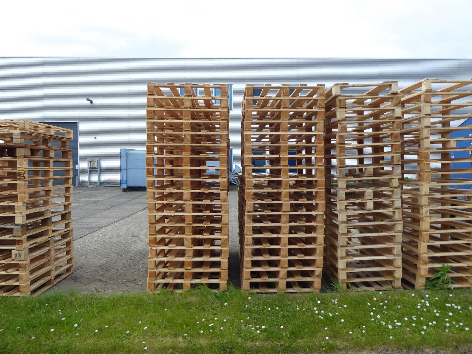 Tarimas de madera apiladas afuera de una nave industrial